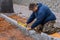 A construction worker laying stone concrete pavers as part of a sidewalk construction project