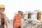 Construction worker looking at tired colleague wiping sweat at site