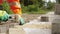 Construction worker makes new sidewalk pavement with stone bricks