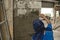 A construction worker or mason plastering wet concrete on a CHB wall with a trowel.