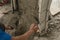 A construction worker or mason smooths out wet concrete placed on top of a CHB wall with a trowel.