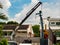 Construction worker and mobile crane lower a steel beam at a construction / building site in suburban Singapore