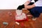 Construction worker and painter with black gloves pours white color from bucket into red bowl for paint mixing.