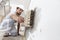 Construction worker painter man with protective helmet, brush in hand restores and paint the wall, inside the building site of a