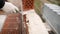 Construction worker. Portrait of mason bricklayer installing red brick with trowel putty knife outdoors. Mortar and brick.