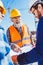 Construction worker in protective uniform discussing building plans with businessman