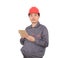 A construction worker with a red hard hat is holding an iPad in hand while standing in front of a white background and looking at