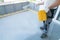 Construction worker renovates balcony floor and spreads chip floor covering on resin and glue coating before applying water