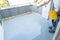 Construction worker renovates balcony floor and spreads chip floor covering on resin and glue coating before applying water