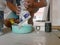 A construction worker`s hands pouring some grout out of the bag into a mixing bowl - grouting tiles