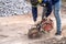 Construction worker in safety glasses and noise-canceling headphones at work. Cutting concrete floor for cable laying with a