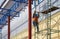 Construction worker with safety workwear climbing on scaffolding for working on roof structure on warehouse building in constructi