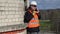 Construction worker with sledgehammer talking on tablet PC