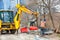 A construction worker team using an excavator unloads concrete curbs at a work site