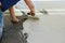 A construction worker troweling mortar onto concrete floor in preparation for laying floor tile