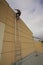 Construction worker wearing fall body safety harness climbing up ladder while conducting inspection