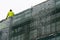 Construction worker works on new building with scaffolding in winter time outdoors