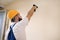 Construction worker works on renovation of apartment. Builder using electric screwdriver and screwing screw out of wall.
