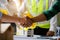 Construction workers, architects and engineers shake hands while working for teamwork and cooperation after completing an