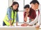 Construction workers , a female architect and two male engineers discussing about the project at office table indoor