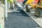 Construction workers placing hot tarmac during roadworks