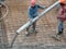 Construction workers pour wet concrete using a hose from the elephant crane or concrete pump crane at the construction site.