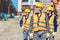 Construction workers in reflective vests and hardhats standing outside, examining the