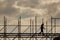 Construction workers silhouette working on iron platform sky background