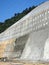 Construction workers are spraying liquid concrete onto the slope surface to form a retaining wall layer.