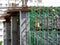 Construction workers wearing safety gear and safety harness while installing scaffolding at a high level