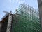 Construction workers wearing safety gear and safety harness while installing scaffolding at a high level