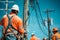 Construction workers in workwear and hard hats are repairing a power line