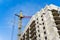 Construction with working crane at background of blue sky, development of modern