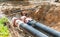 Construction works on large iron pipes at a depth of excavated trench