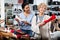 Consultant in shoeshop helping old woman to choose footwear