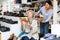 Consultant in shoeshop helping old woman to choose footwear