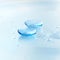 Contact lenses and water drops on light blue background. Eyewear, eyesight and vision, eye care and health, ophthalmology and