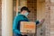 Contactless delivery during COVID-19 pandemic lockdown concept. Courier wearing mask and gloves holds a parcel