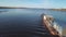 Container barge sailing on a wide beautiful river on sunset sky background. Clip. Concept of transportation, aerial view