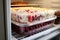 Container with berry pie in the refrigerator. Frozen semi-finished baked goods with juicy berries and cream for long