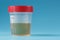 A container for biomaterials with a urine analysis and a red lid on a blue background
