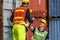 Container Depot chief  talking with foreman in safety vast and safety helmet in Container shipyard