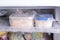 A container with food in the freezer. A freezer packed with chicken, soup and various frozen food