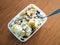 A container with healthy oatmeal, slices of banana, cashew nuts and cranberries on a wooden table