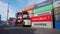 A container-laden reachstacker drives along an open-air container warehouse