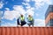 Container operator wearing white helmet and reflection shirt and holding tablet doing routine inspection while working in