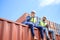 Container operators wearing helmets and safety, vests control via walkie-talkie workers in container yards. Cargo Ship Import