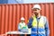 Container operators wearing helmets and safety, vests control via walkie-talkie workers in container yards. Cargo Ship Import