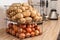 Container with potatoes and onions on kitchen counter. Orderly storage