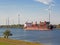 Container ship on a river with wind turbines in the background